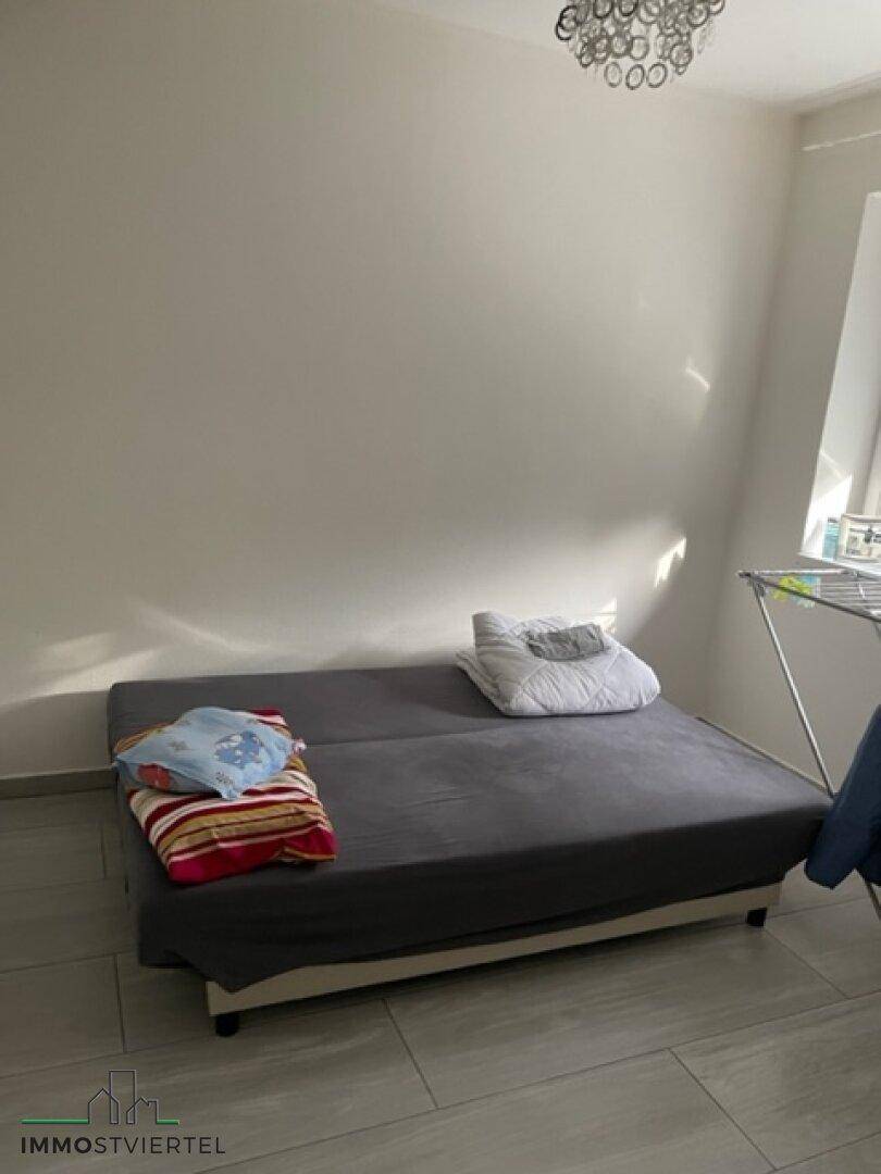 Einfaches Zimmer mit Schlafsofa und Fliesenboden, ideal als Gästezimmer nutzbar.