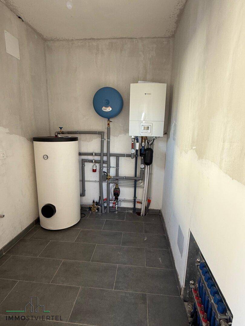 Hauswirtschaftsraum mit Warmwasserbereiter, Heizungsanlage und Fliesenboden.