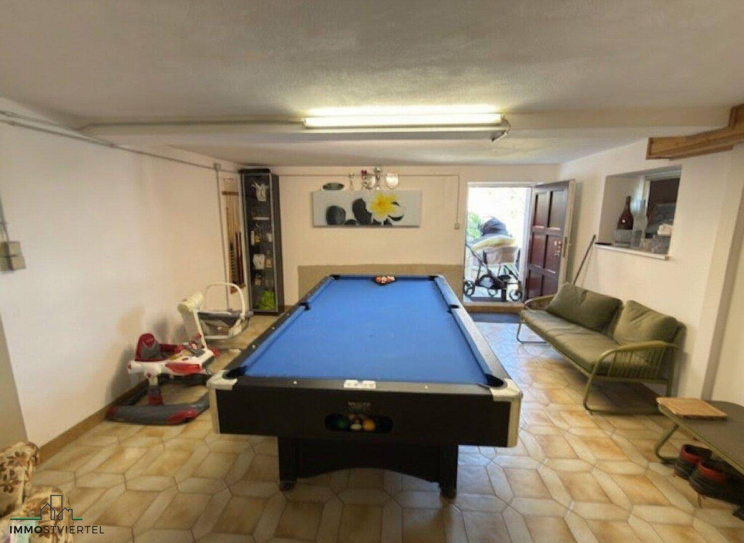 Geräumiger Hobbyraum im Keller mit Billardtisch und Sitzgelegenheiten.