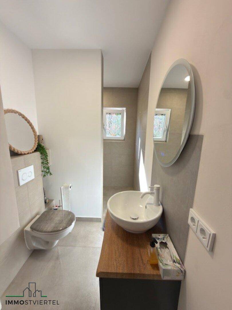 Modernes Gäste-WC mit Wand-WC, Waschbecken und Spiegel.