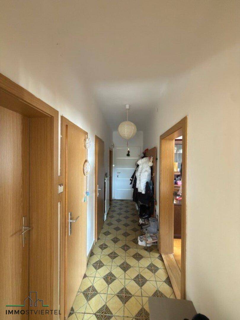 Flur mit gemusterten Fliesen, Holztüren und Garderobe.