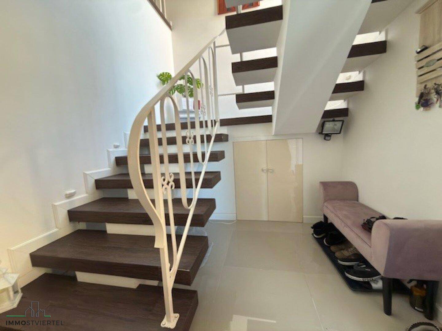 Moderne Treppe mit Holzstufen und elegantem Geländer, die die Stockwerke verbindet.