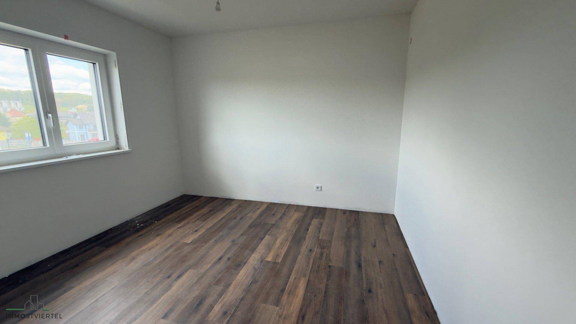 Geräumiges Schlafzimmer mit Laminatboden und großem Fenster für viel Tageslicht.