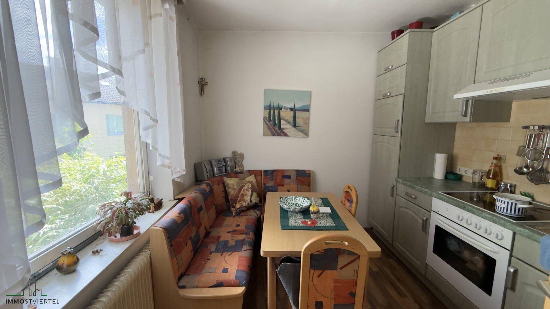 Kleine Wohnküche mit Einbauschränken, Esstisch und Fenster, ideal für den täglichen Gebrauch.