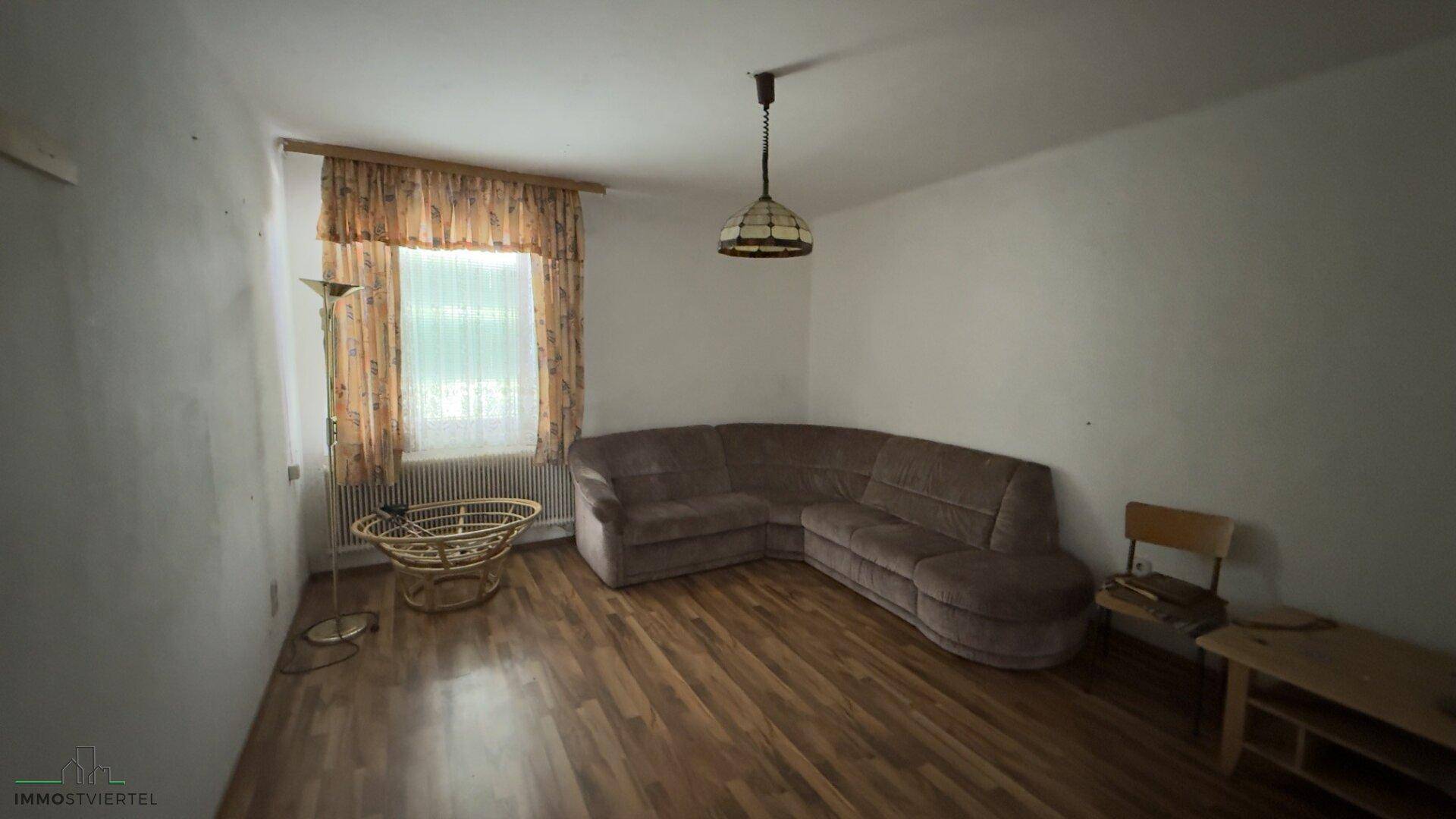 Wohnzimmer mit Laminatboden, Ecksofa und Fenster, bietet eine gemütliche Atmosphäre.