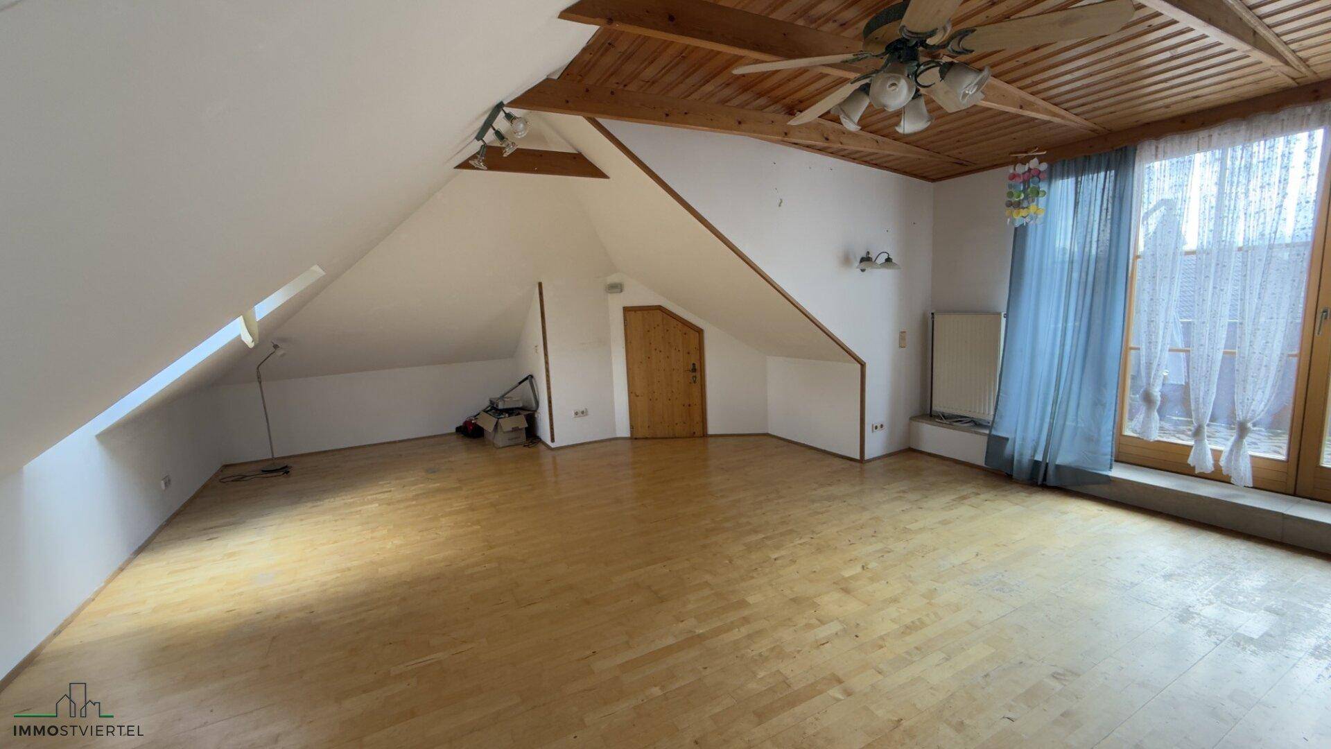 Heller und geräumiger Wohnbereich im Dachgeschoss mit Holzbalkendecke und Parkettboden.
