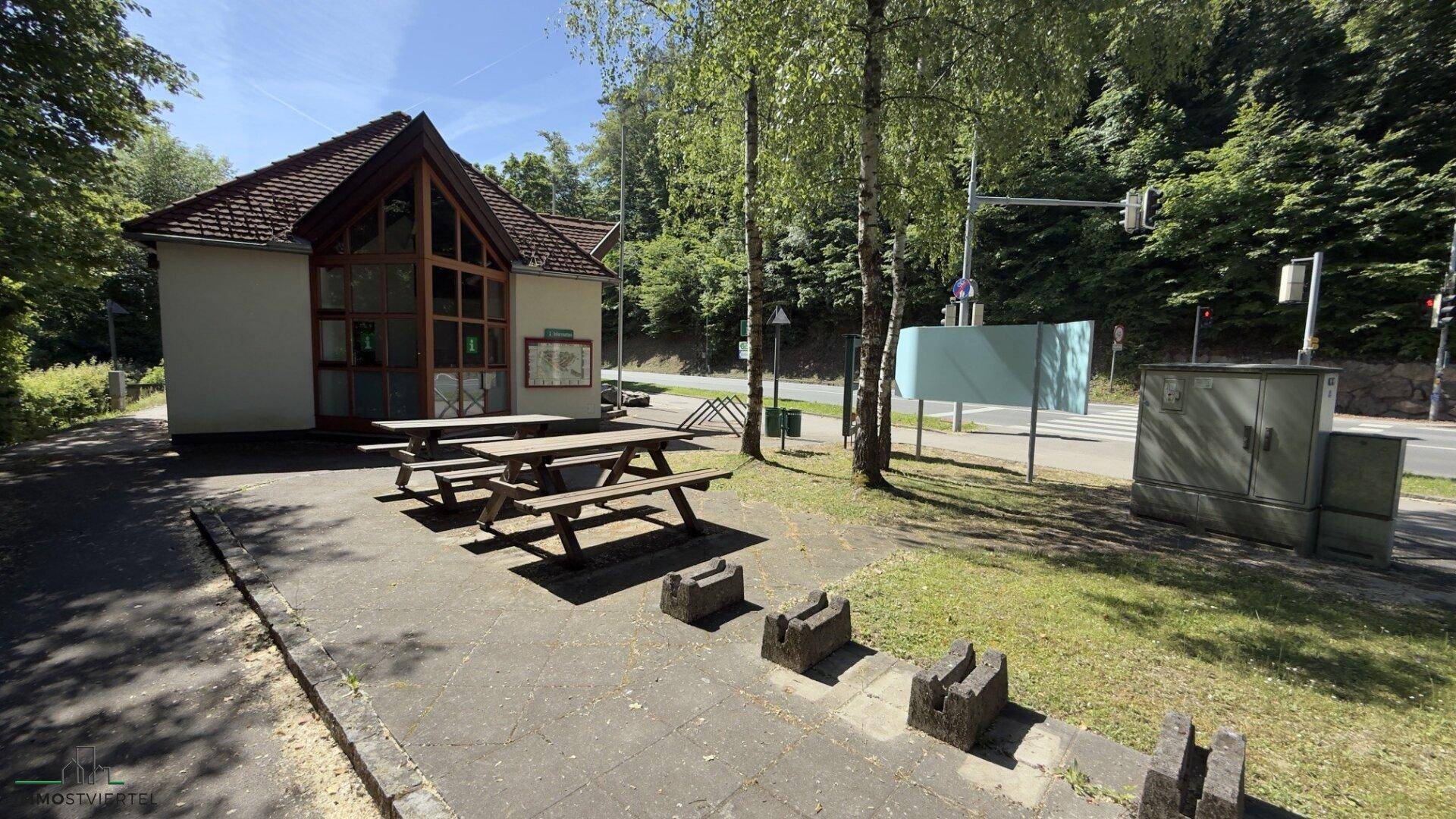 Außenbereich mit Holztischen und Bänken, ideal für Gäste, um im Freien zu sitzen und zu essen.