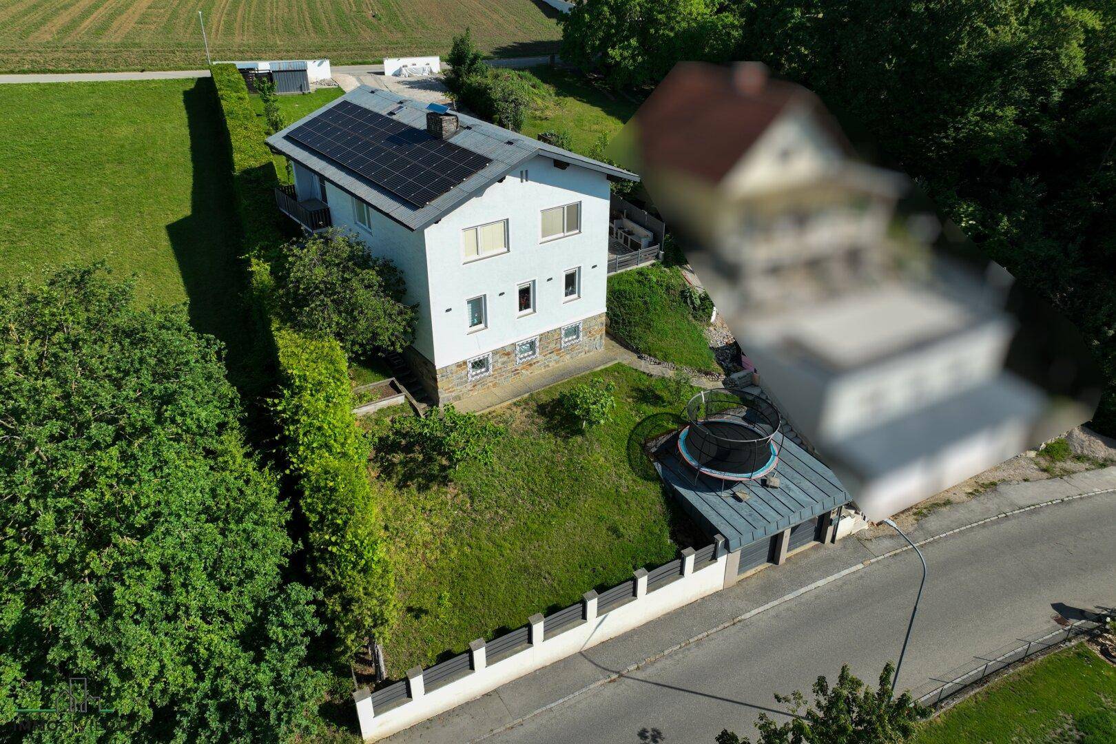 Nahaufnahme eines Einfamilienhauses von oben mit Photovoltaikanlage, Garten und Trampolin.