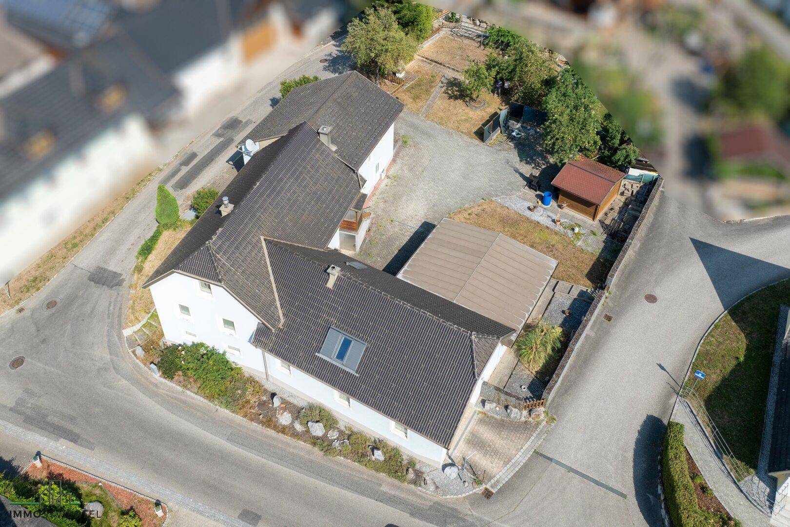 Vogelperspektive des Anwesens mit Wohnhaus, Carport und gepflegtem Grundstück.
