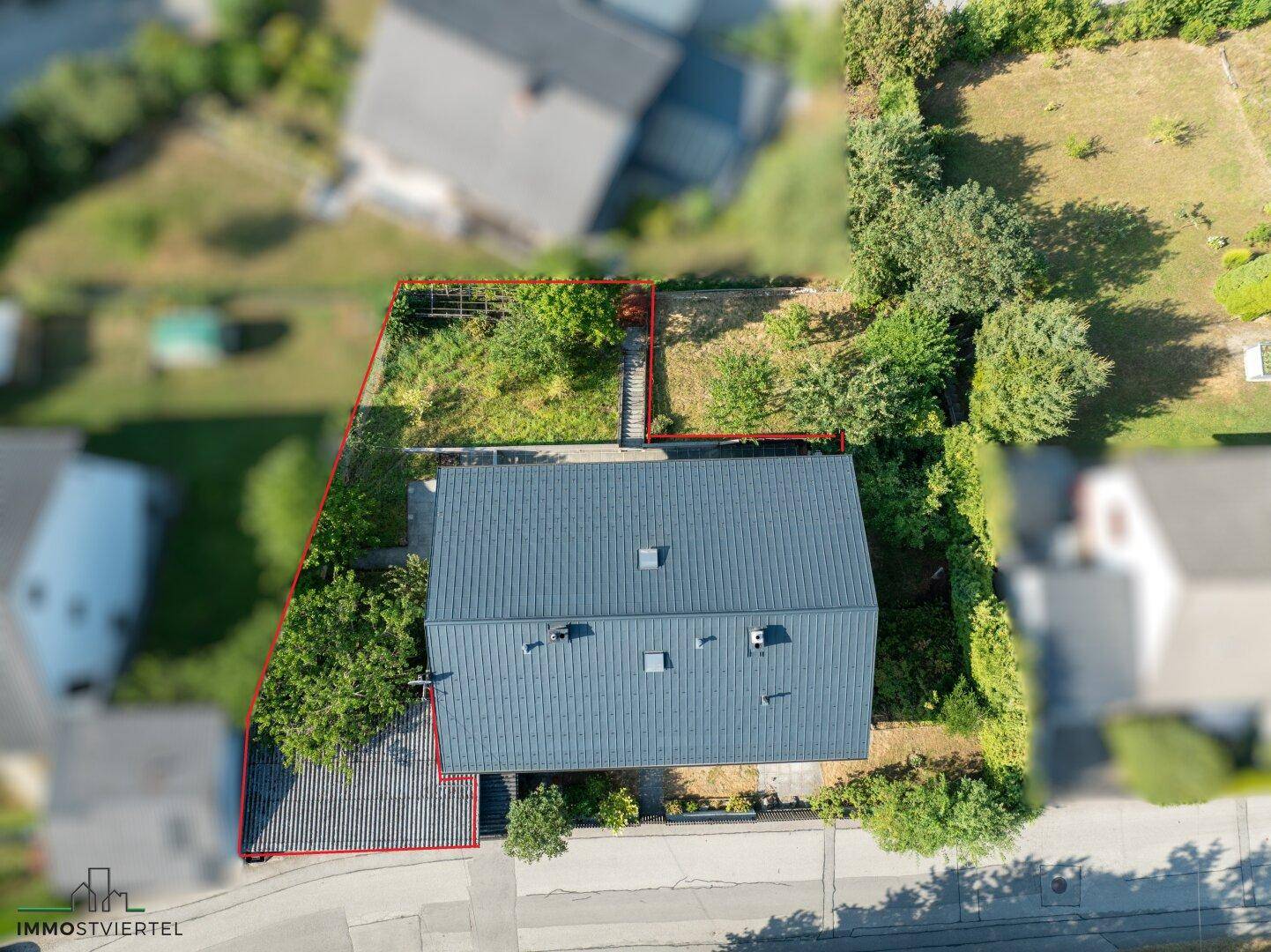 Luftaufnahme des Einfamilienhauses mit Garten und umliegender grüner Landschaft.