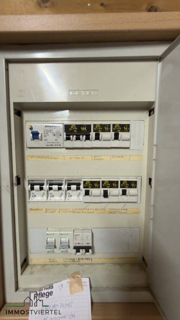 Elektrischer Sicherungskasten mit mehreren Schaltern und handschriftlichen Notizen.