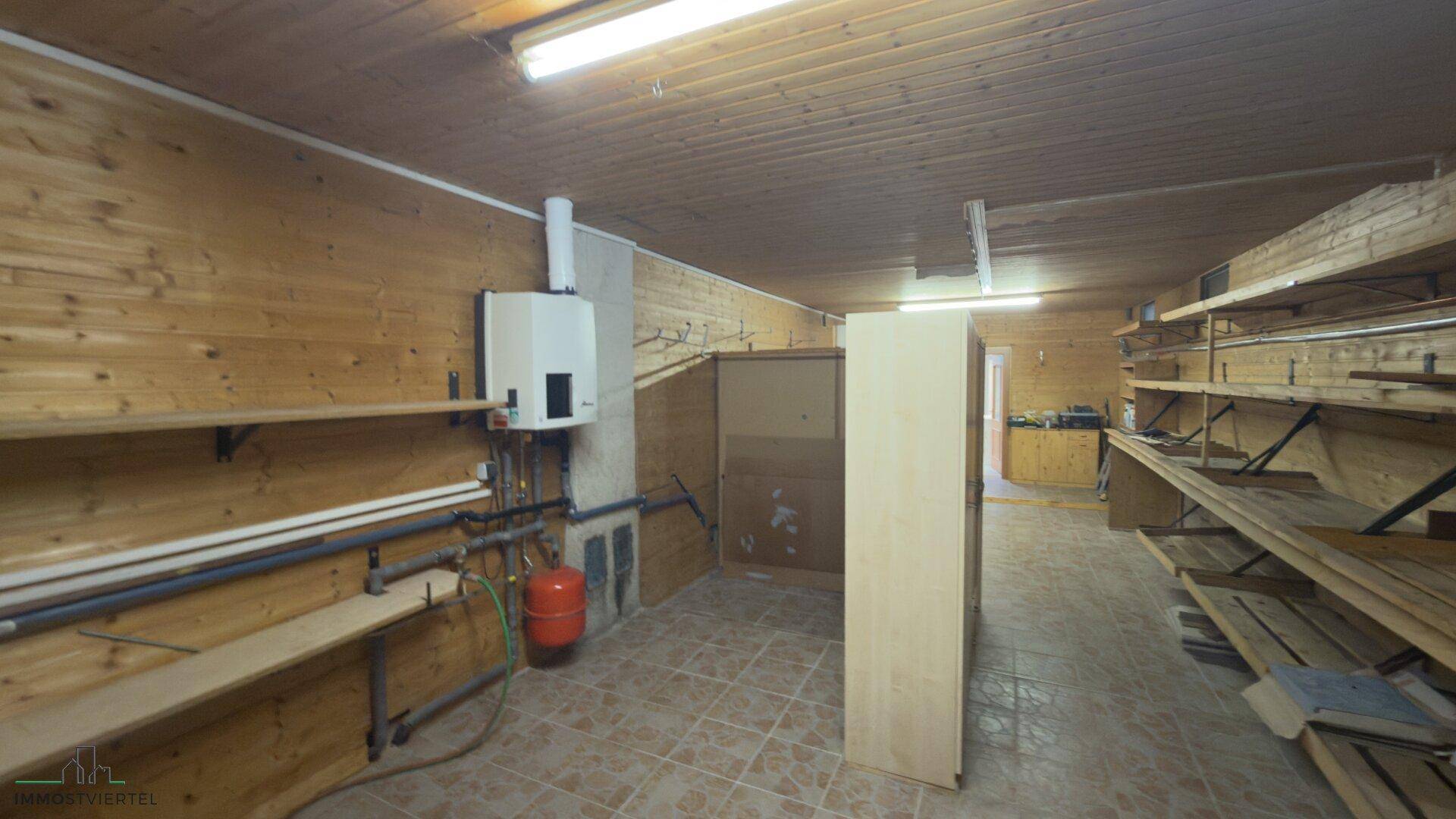 Geräumiger Hauswirtschaftsraum mit Holzverkleidung, Regalen und Heizungsanlage.