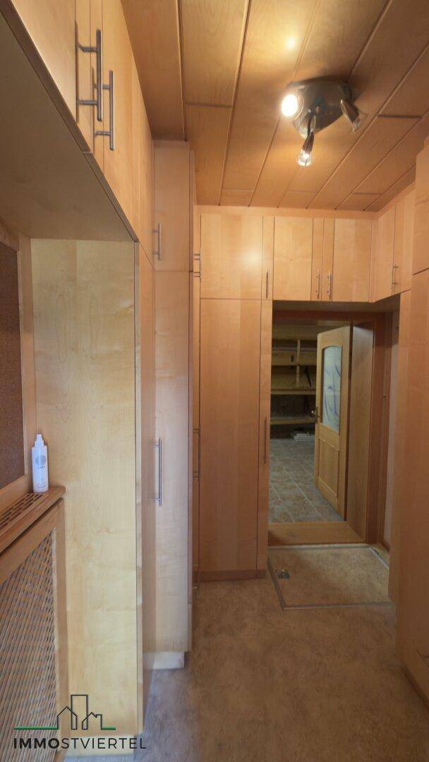 Flur mit Einbauschränken aus hellem Holz und Deckenbeleuchtung.