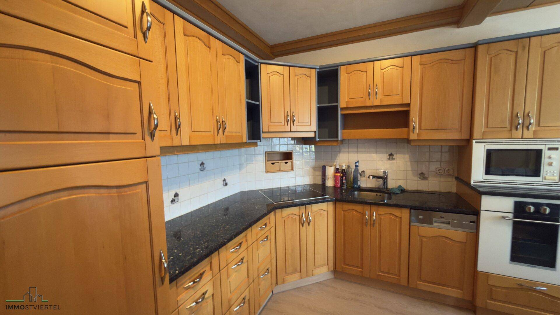 Traditionelle Holzküche mit dunkler Granitarbeitsplatte und integrierten Geräten.