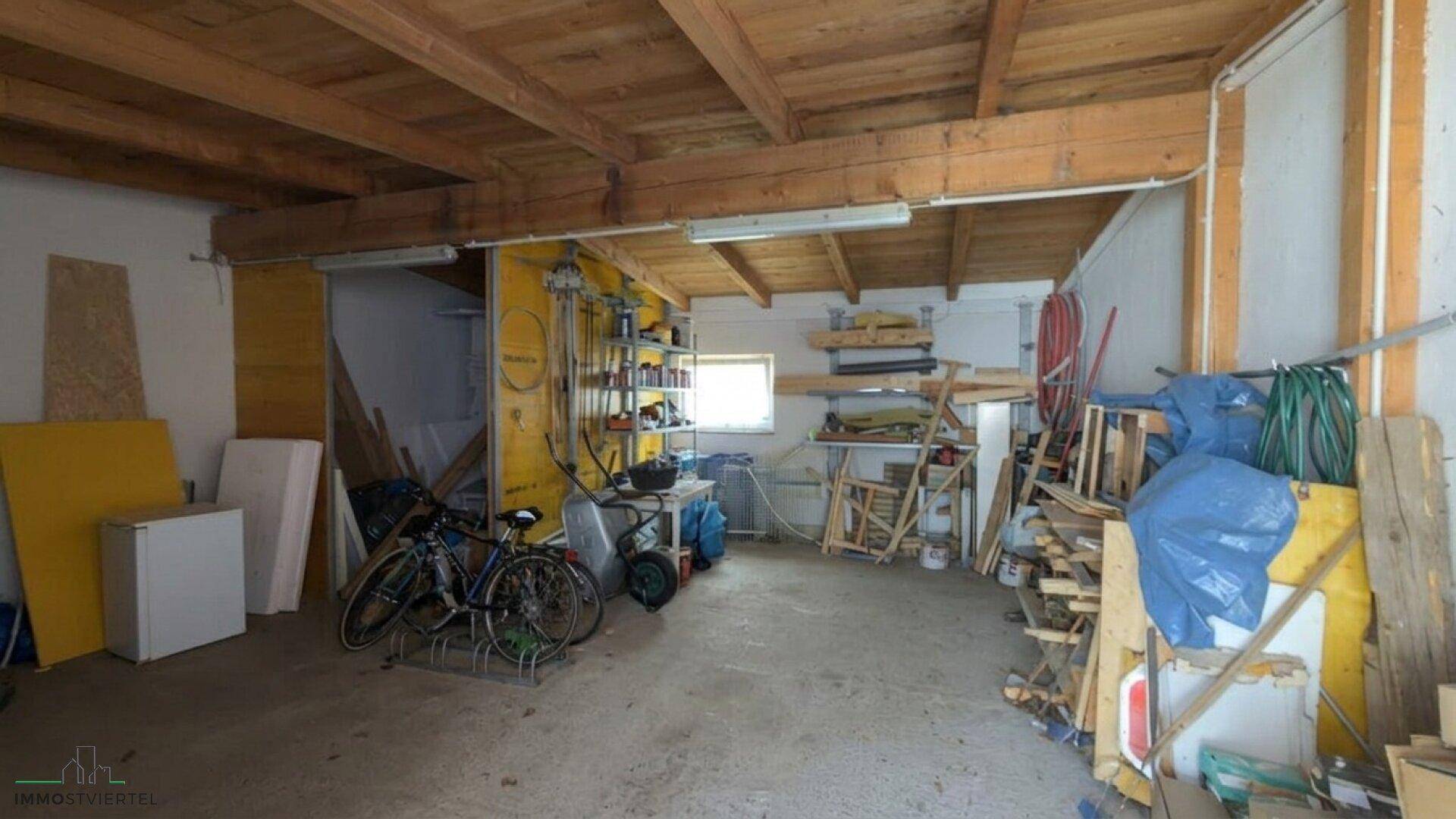 Großer Werkstatt- oder Lagerbereich mit sichtbaren Holzdeckenbalken und Werkzeugen.
