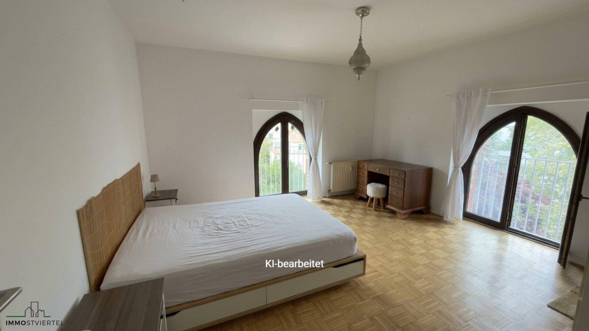 Helles Schlafzimmer mit Parkettboden, Doppelbett und großen Rundbogenfenstern, modern eingerichtet.