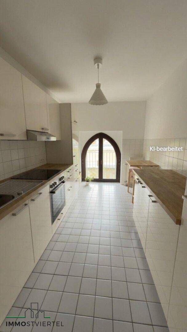 Schmale Küche mit weißen Schränken, Holz-Arbeitsplatten und Fliesenboden, mit Fenster.