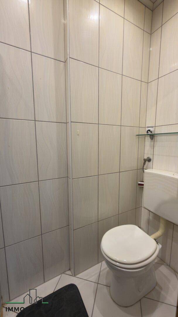 Kleines Gäste-WC mit Wandfliesen und einfacher Ausstattung, praktisch und sauber.