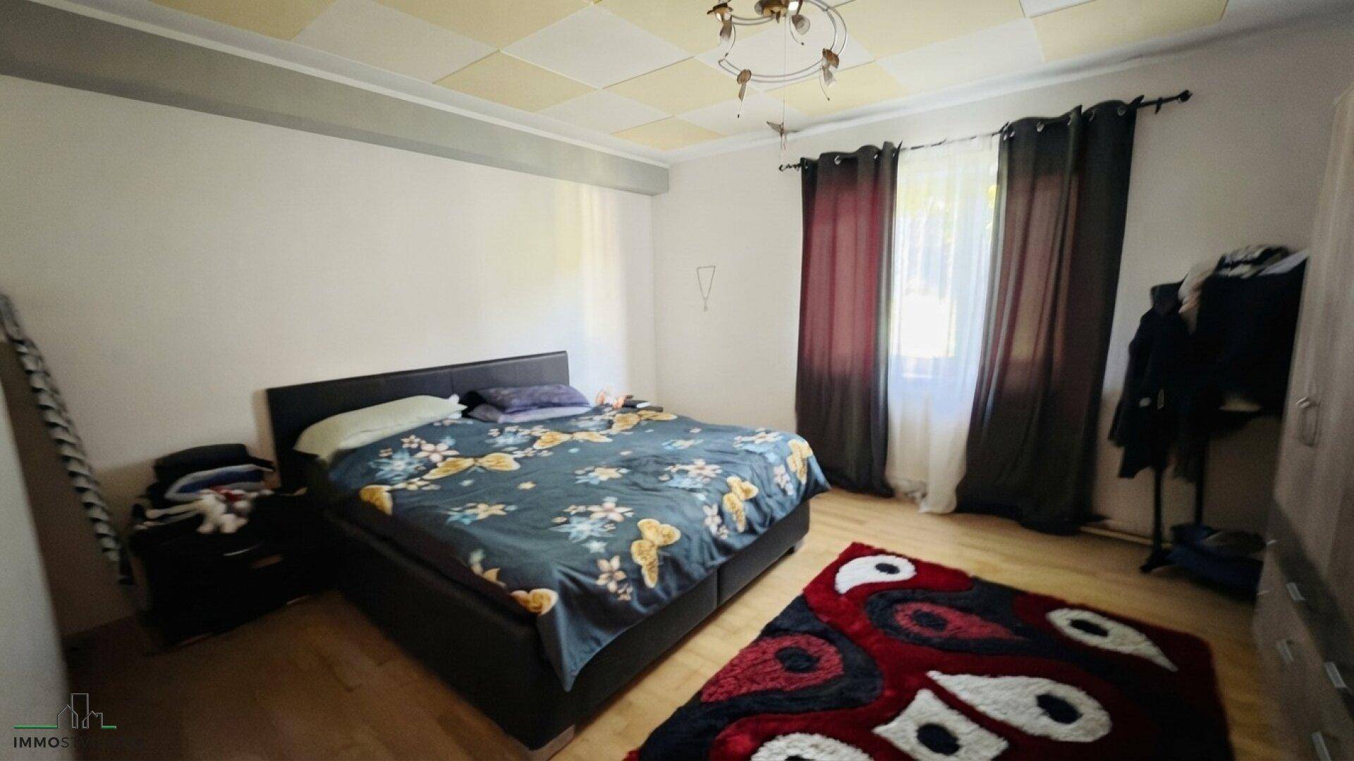 Schlafzimmer mit Doppelbett, gemusterter Decke und Holzboden, gemütlich eingerichtet.