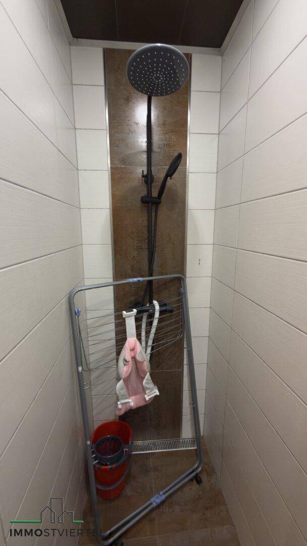 Moderne Duschkabine mit Regendusche und Fliesenwänden, sauber und funktional.