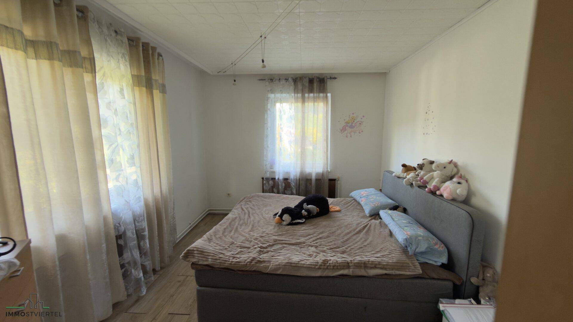 Helles Schlafzimmer mit Doppelbett und großen Fenstern, gut beleuchtet.