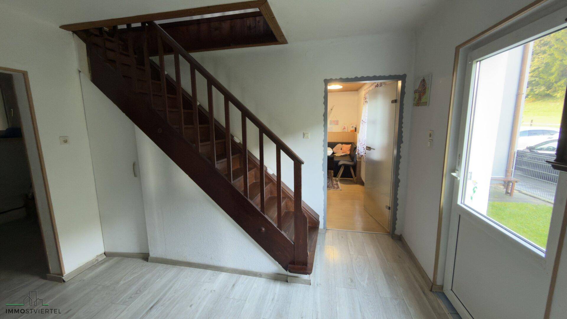 Eingangsbereich mit Holztreppe und hellem Bodenbelag, einladend gestaltet.