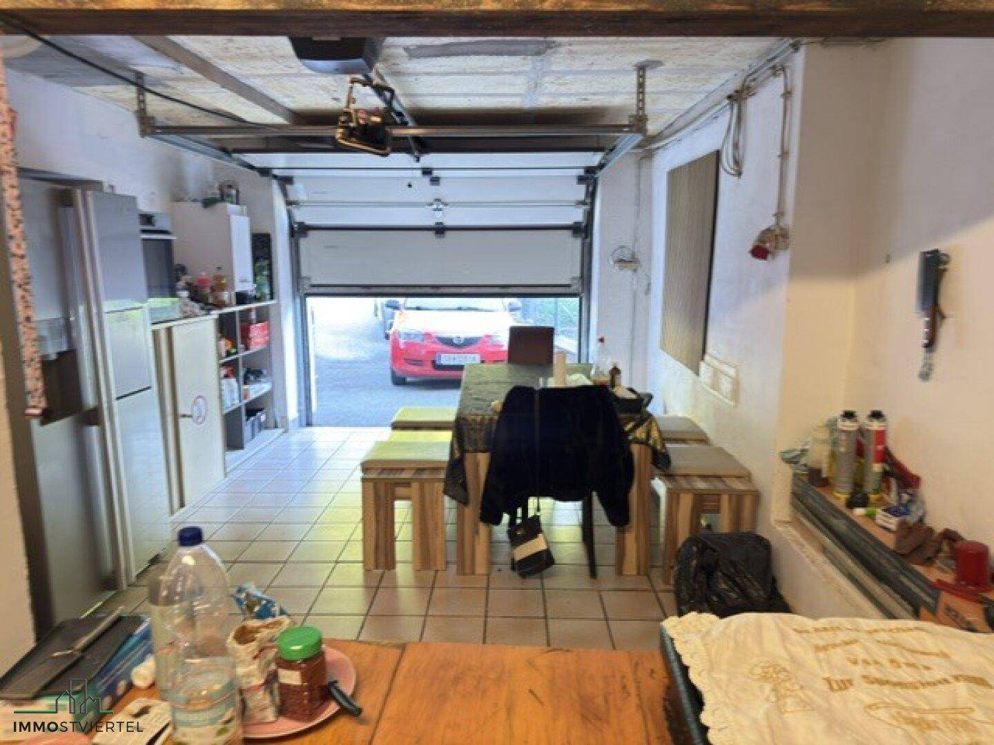 Umfunktionierte Garage mit Essbereich und Lagerfläche, die zum Außenbereich hin offen ist.