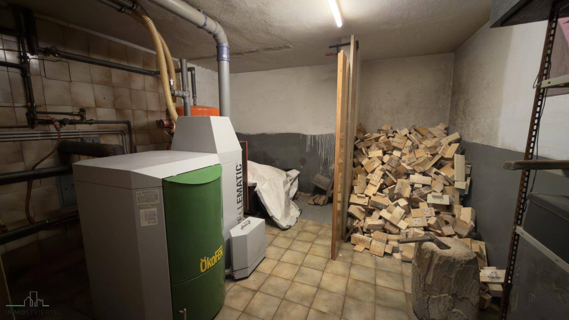 Heizraum mit Pelletkessel und Holzvorrat im Kellerbereich, funktional und geräumig.