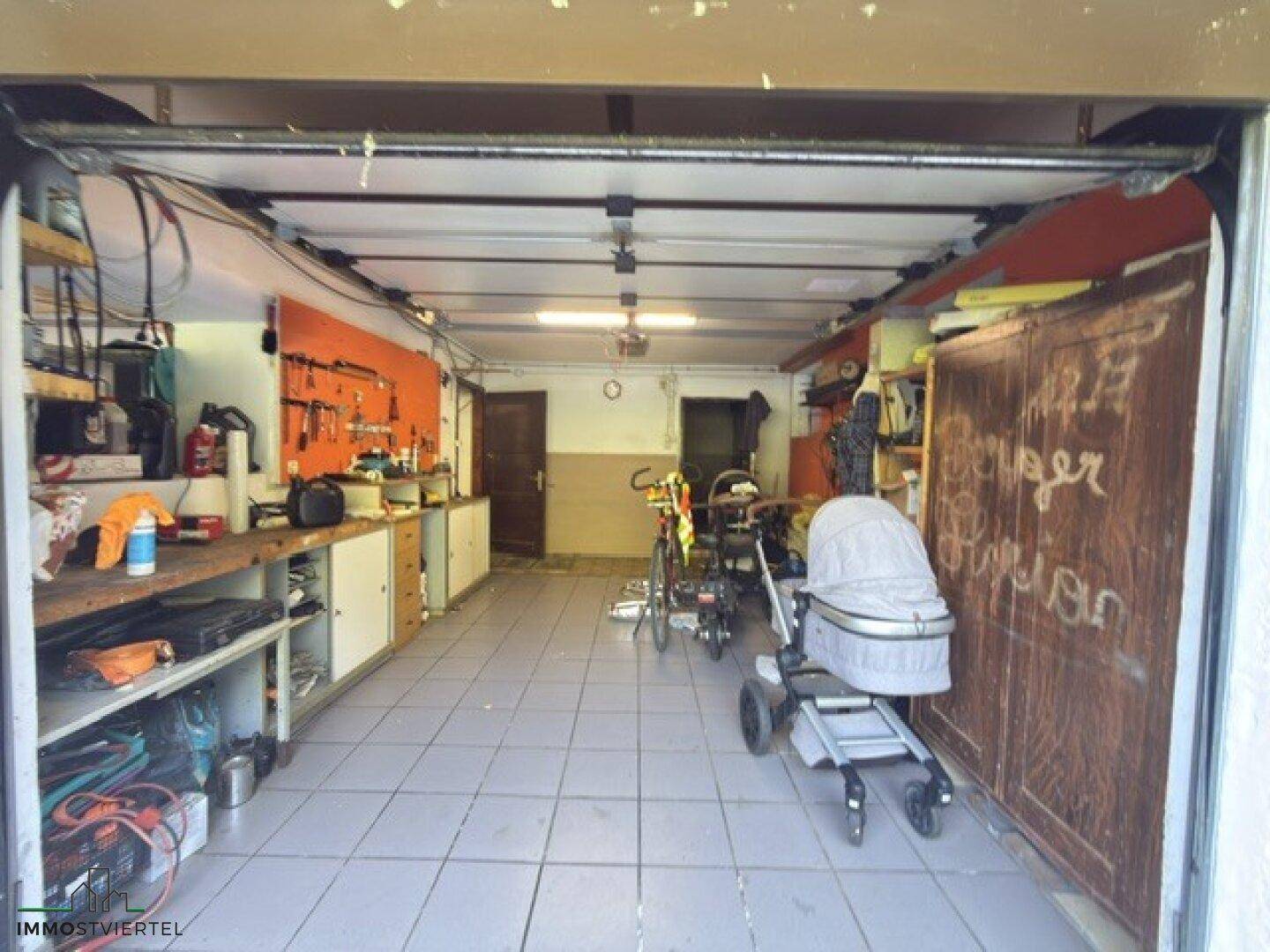 Geräumige Garage mit Werkbank, Stauraum und Fliesenboden, vielseitig nutzbar.