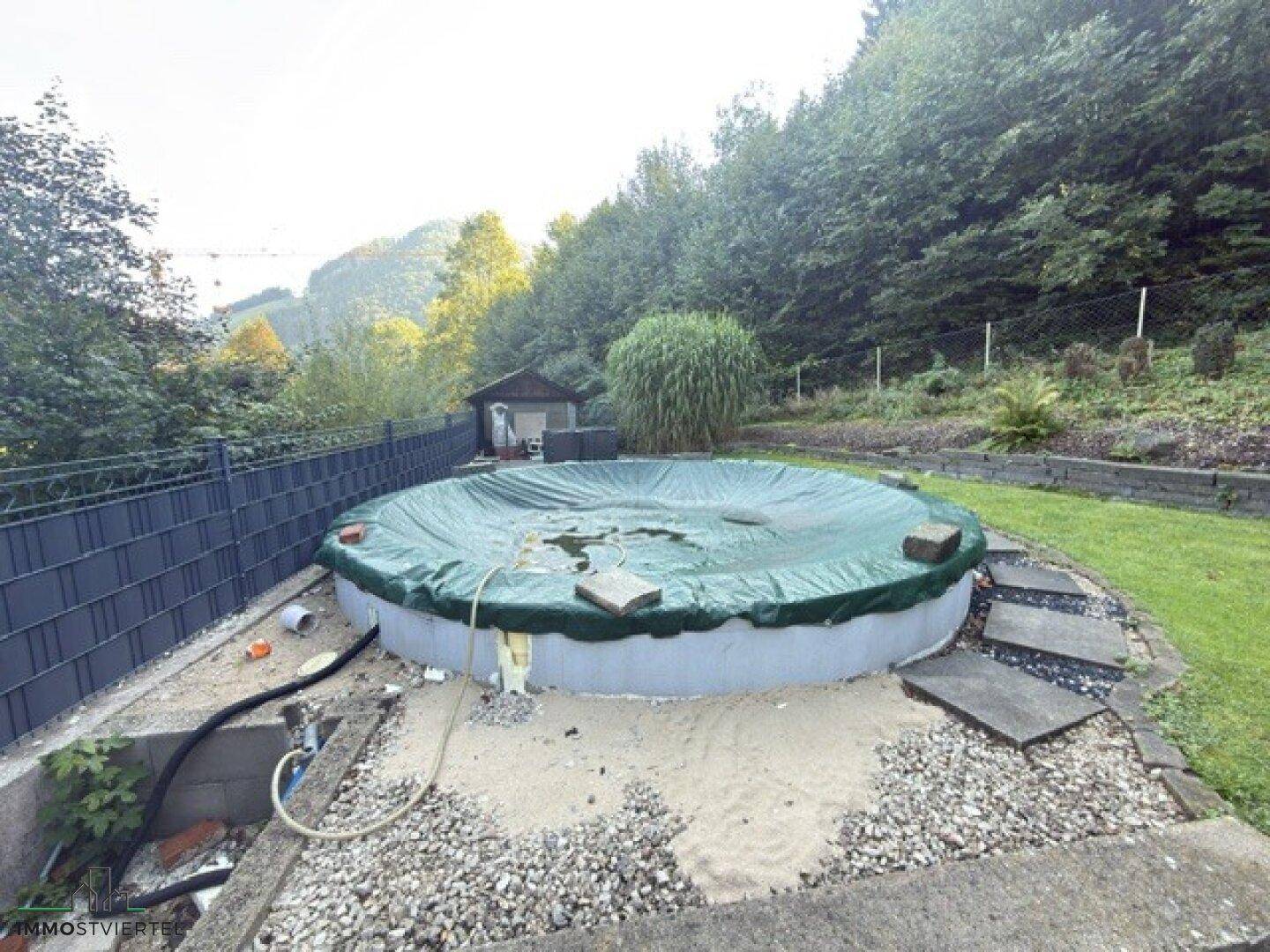 Runder Aufstellpool im Gartenbereich, umgeben von Grünflächen und Bäumen.