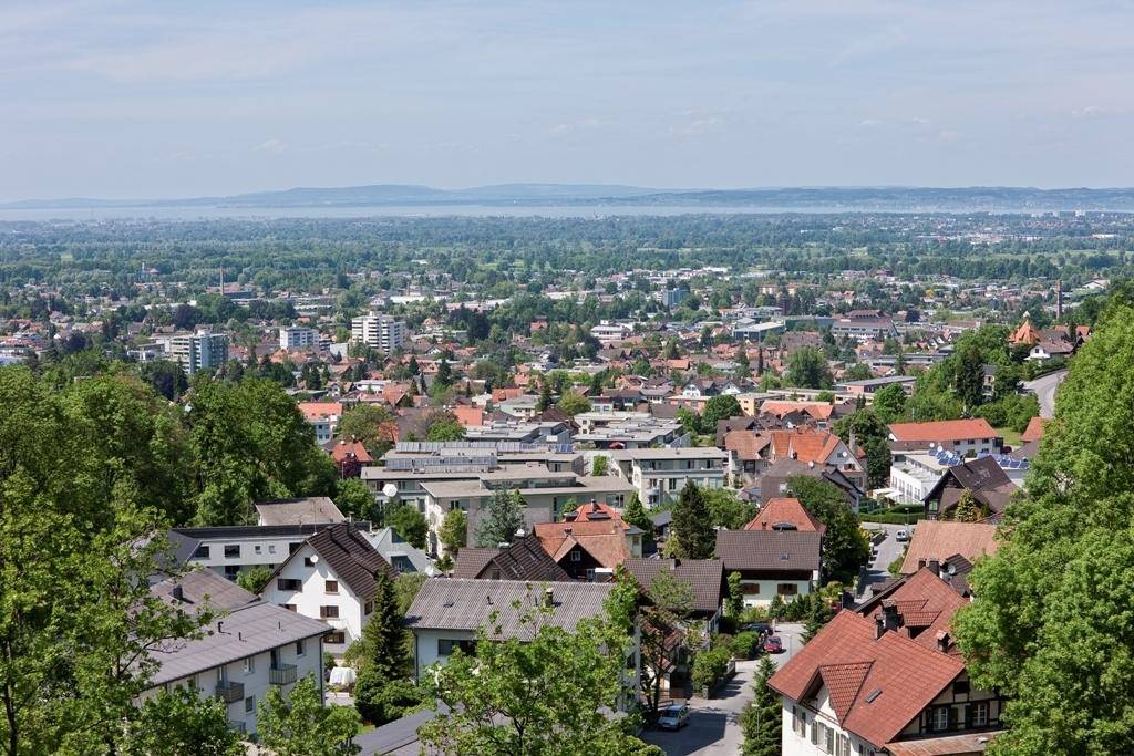 Weitläufiger Blick über eine Stadt mit vielen Häusern und einem großen See oder Meer in der Ferne.