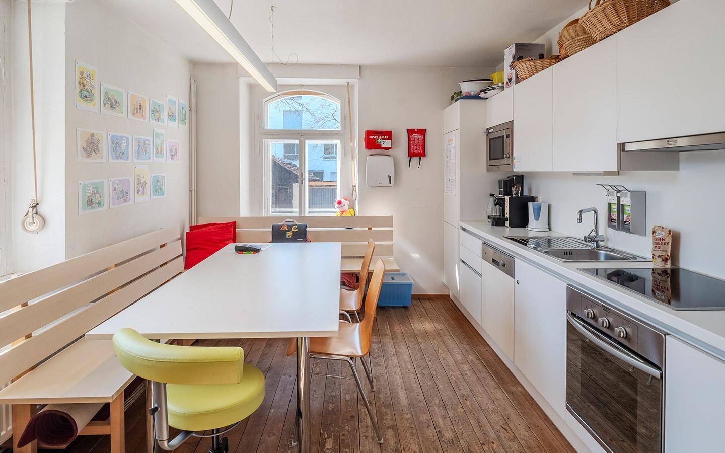 Funktionale Küche mit weißen Schränken und einer langen Sitzbank, ideal für gemeinsame Mahlzeiten.