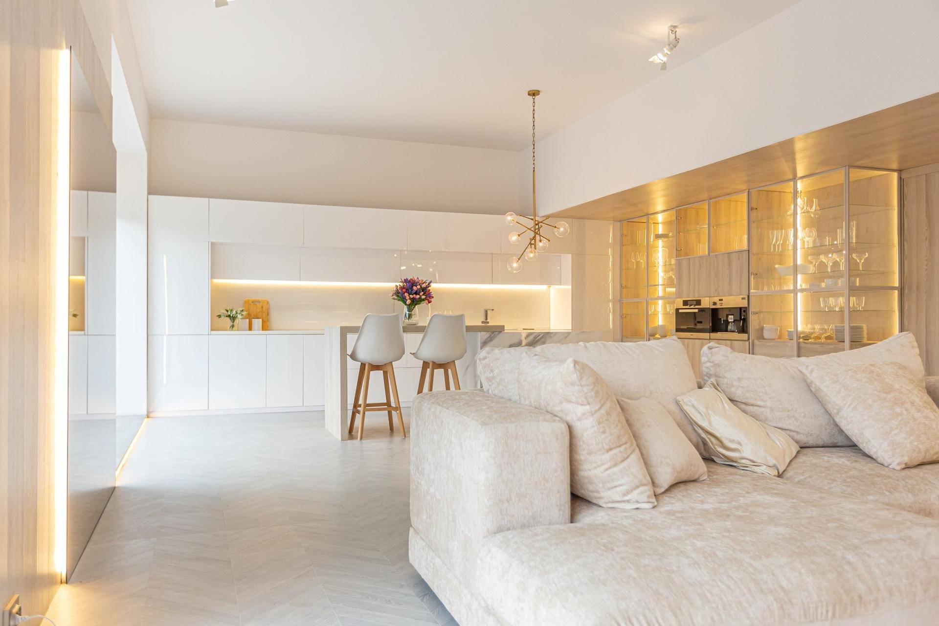 Geräumiger Wohnbereich mit offener Küche, elegantem Sofa und stilvoller Beleuchtung.