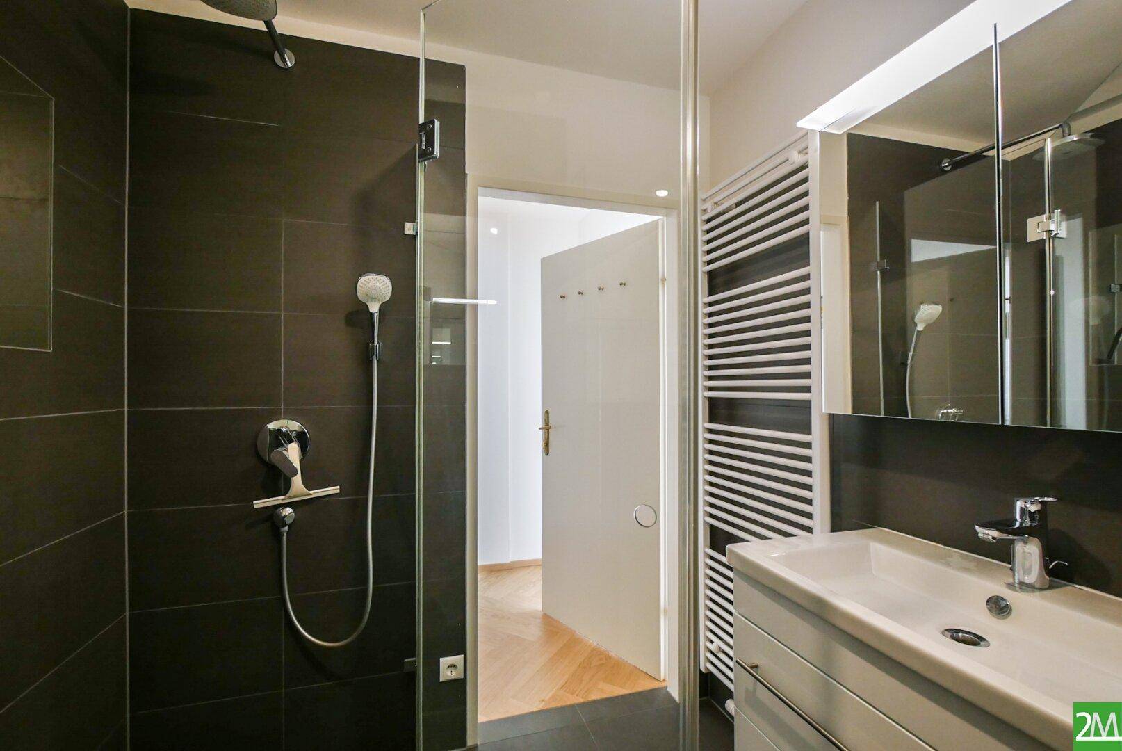 Modernes Badezimmer mit Duschbereich, Waschtisch und beheiztem Handtuchhalter.