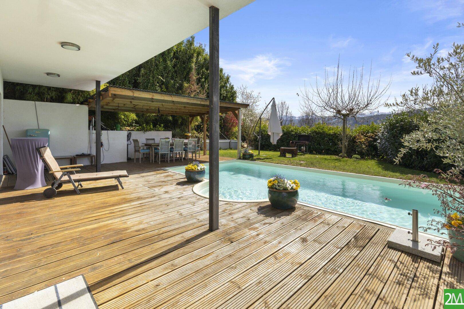 Große Holzterrasse mit Pool und überdachtem Essbereich im Freien.