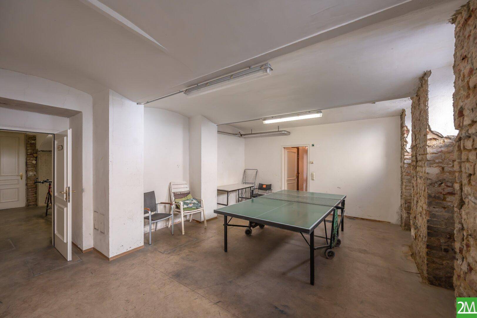 Geräumiger Kellerraum mit Tischtennisplatte und unverputzten Ziegelwänden, ideal für Freizeit.