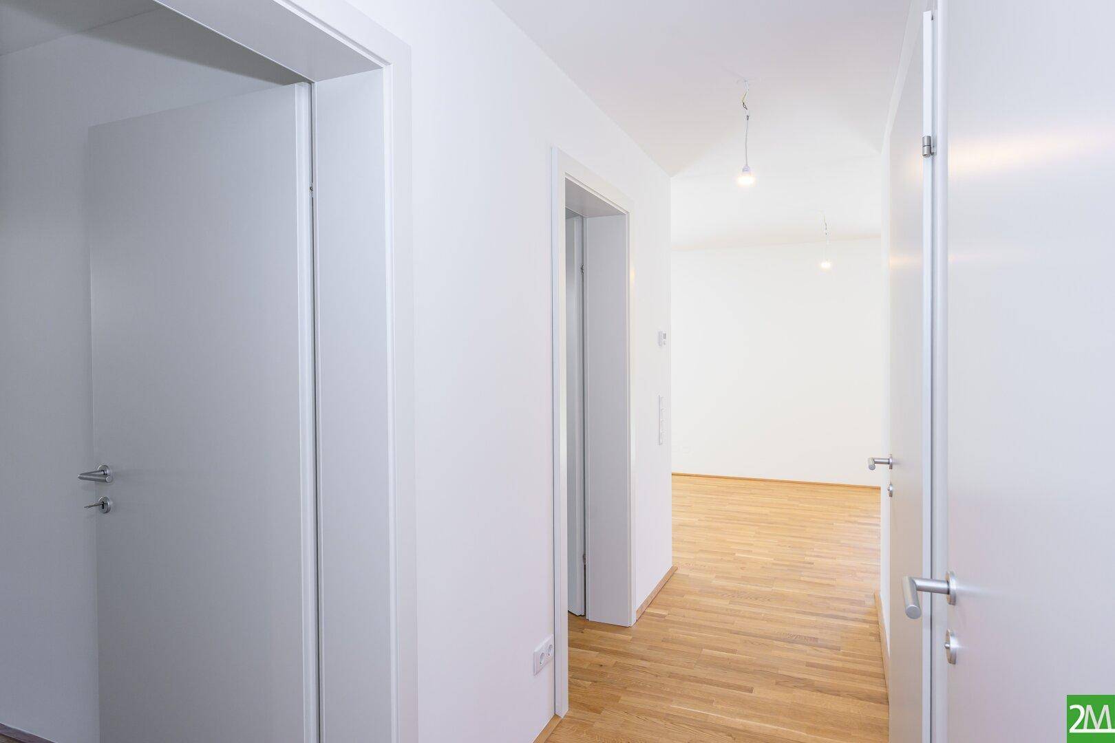 Heller Flur mit Holzboden und mehreren Türen zu den angrenzenden Räumen.