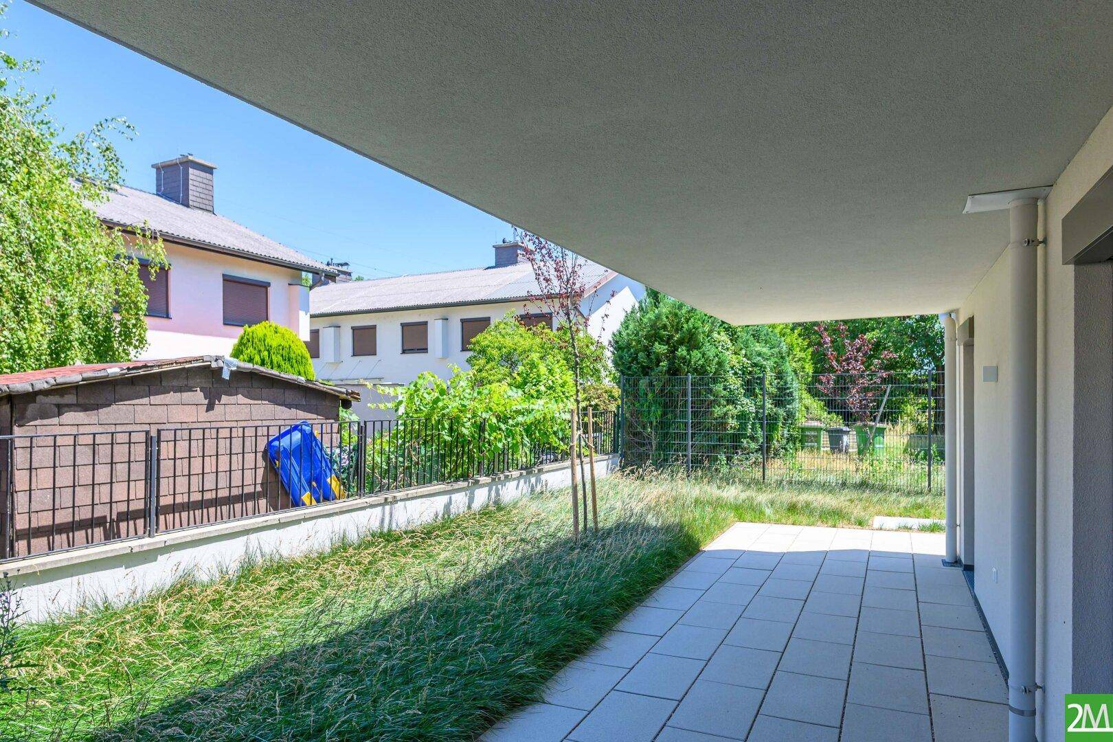 Überdachte Terrasse mit gepflastertem Bereich und Blick auf die umliegenden Gärten.