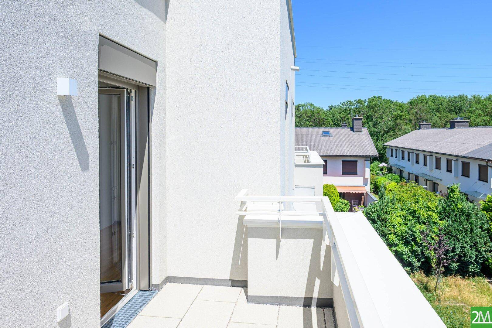 Sonniger Balkon mit Blick ins Grüne und auf die umliegenden Häuser, perfekt zum Entspannen.