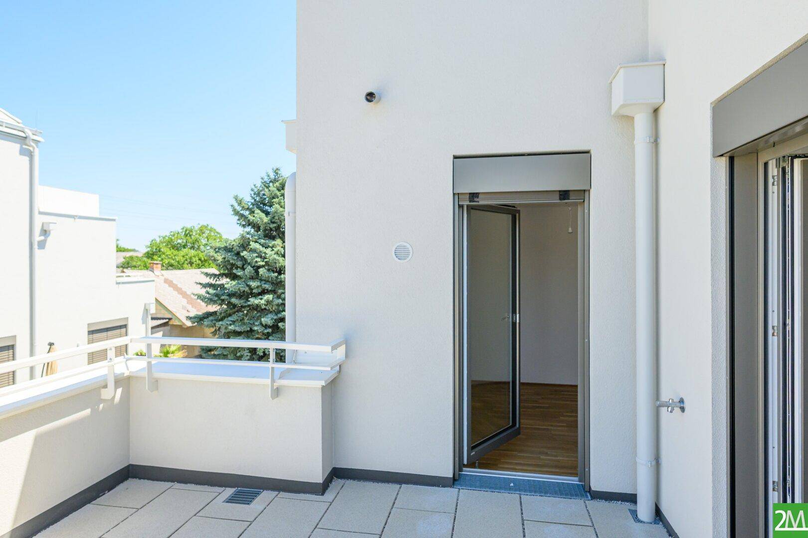 Geräumige, geflieste Terrasse mit Geländer und Zugang zum Innenbereich, ideal zum Entspannen.