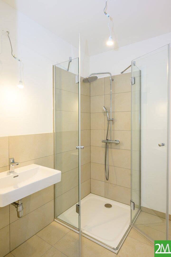 Modernes Badezimmer mit begehbarer Dusche, Einzelwaschbecken und beigefarbenen Fliesen.