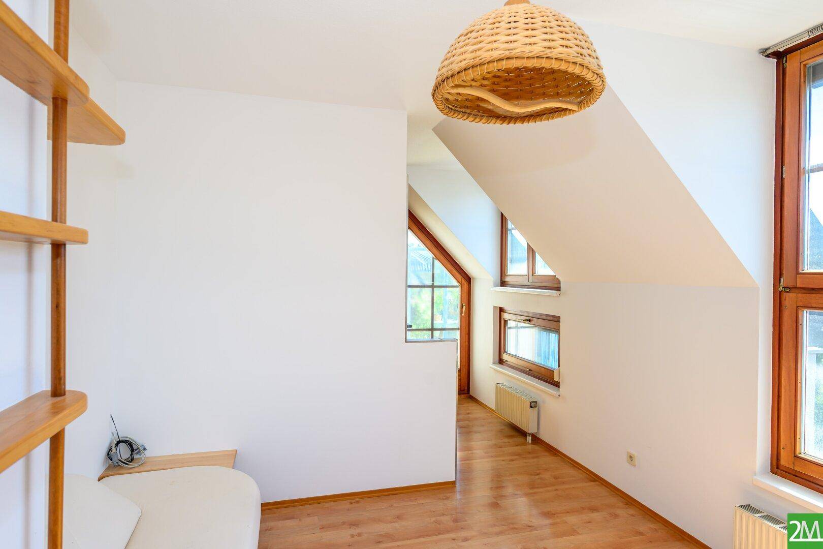 Heller Raum mit Holzboden, Dachschrägen und großen Fenstern, bereit zur individuellen Gestaltung.