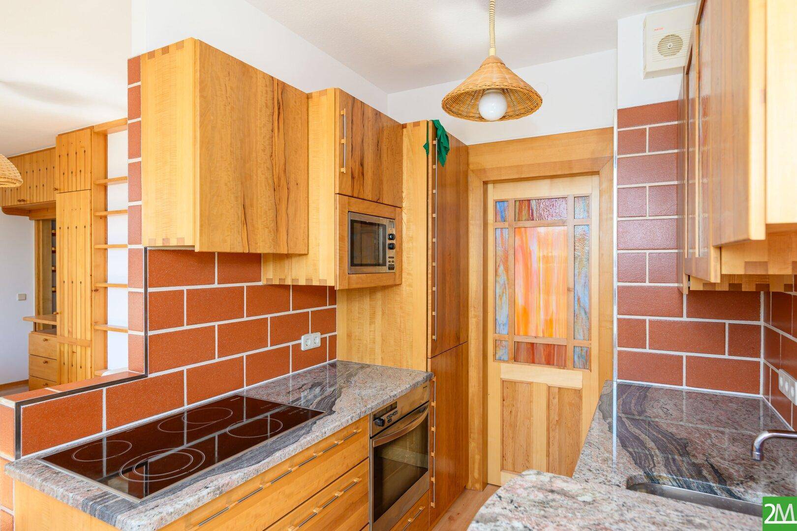 Küche mit Holzschränken, Granitarbeitsplatte und integrierten Geräten im rustikalen Stil.