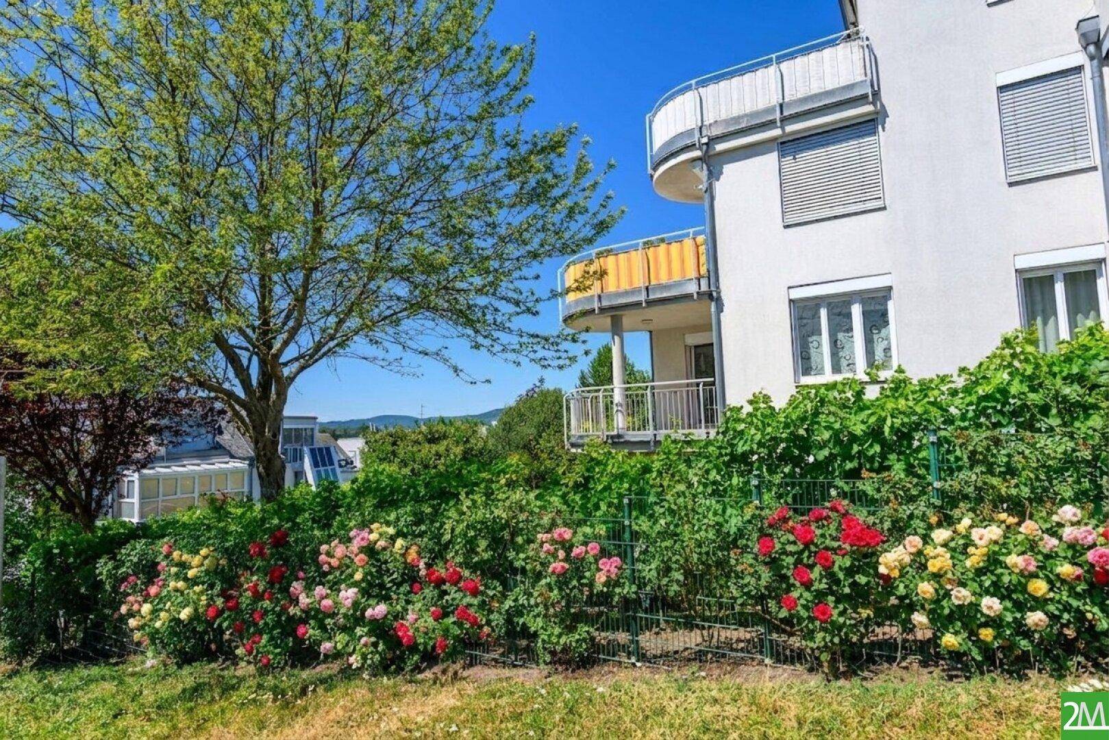 Attraktive Wohnanlage mit Balkonen und gepflegten Rosenbeeten im Vorgarten.