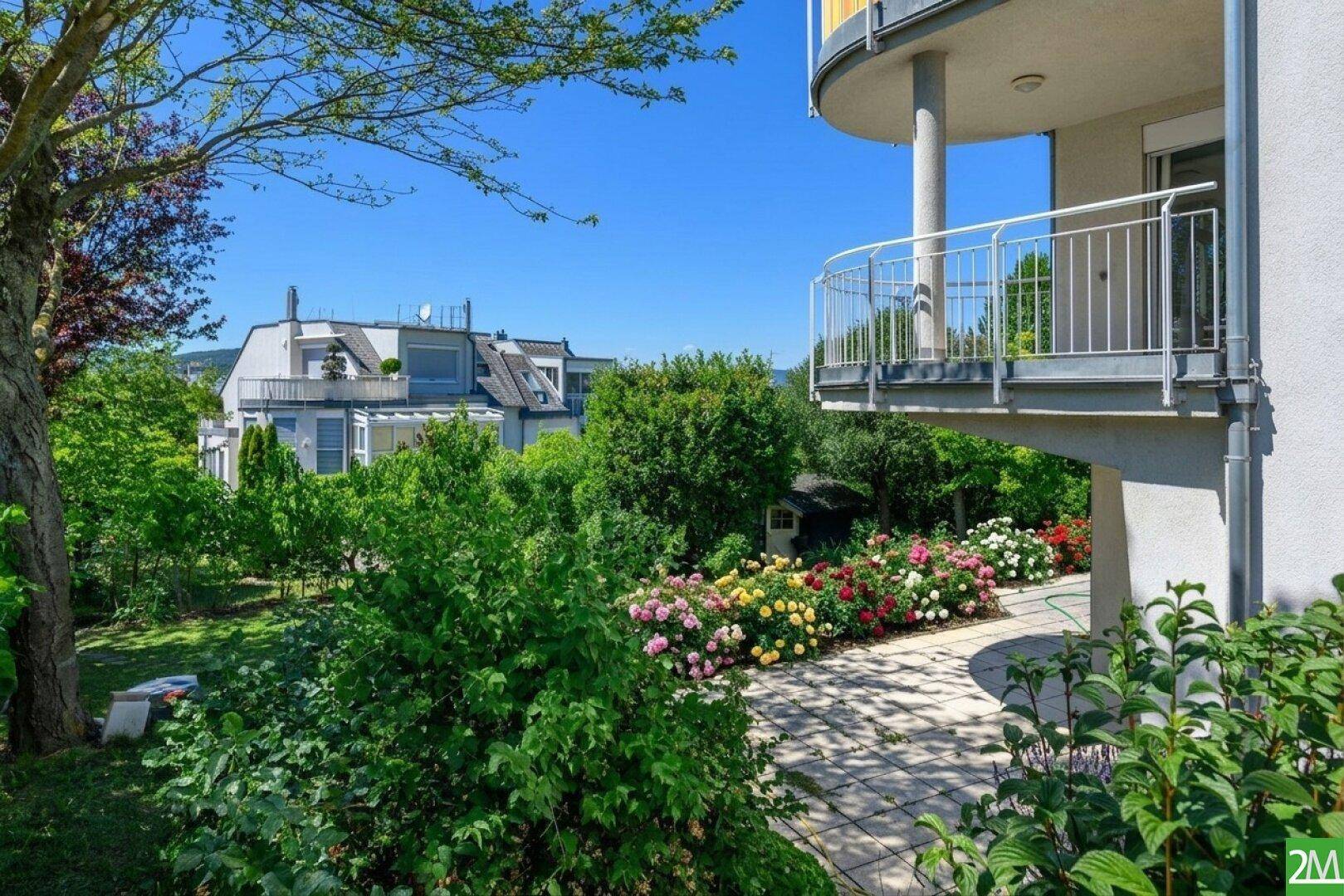 Gepflegter Gartenbereich mit blühenden Rosen und Blick auf die Wohnanlage.