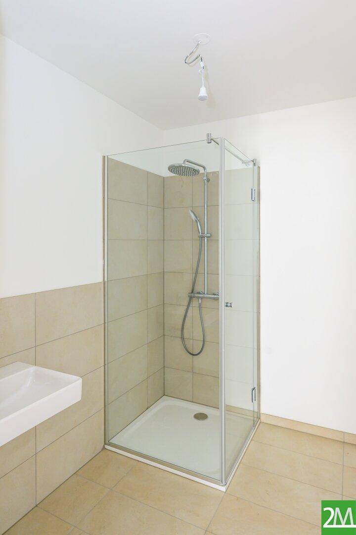 Modernes Badezimmer mit Duschkabine, Regendusche und hellem Fliesenboden.