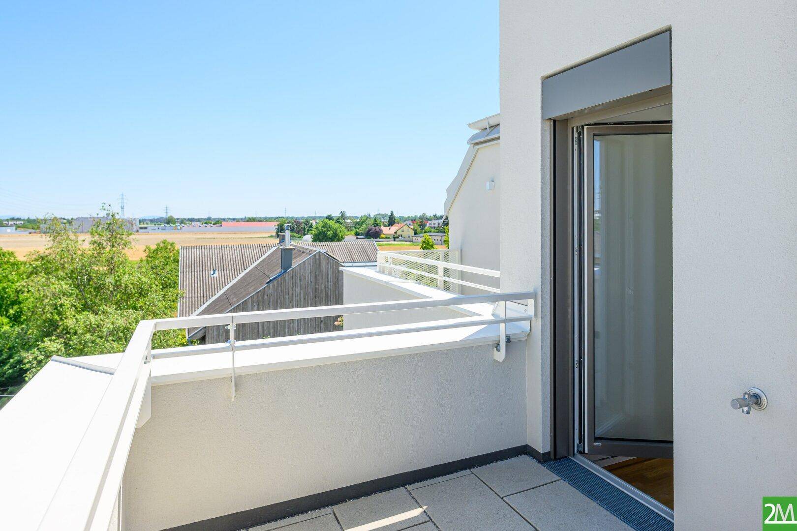 Leerer Balkon mit Fliesenboden und weitem Blick über die umliegende Landschaft.