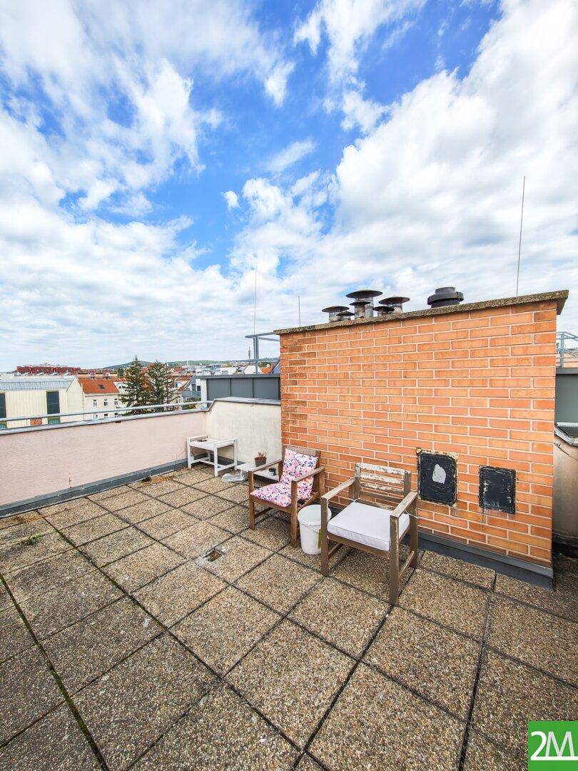 Dachterrasse mit Betonplatten und einer Ziegelmauer, bietet Platz für Outdoor-Möbel und Entspannung.
