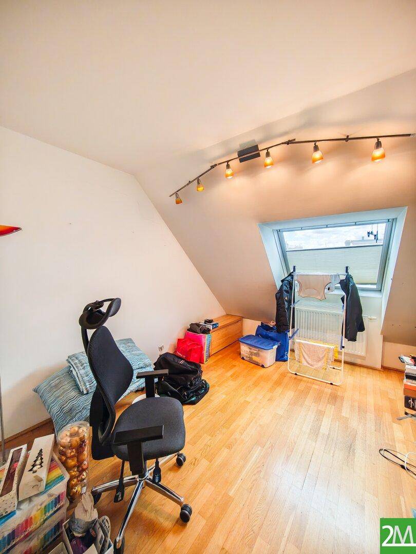 Dachzimmer mit Holzboden, Bürostuhl und Dachfenster, bietet vielseitige Nutzungsmöglichkeiten.