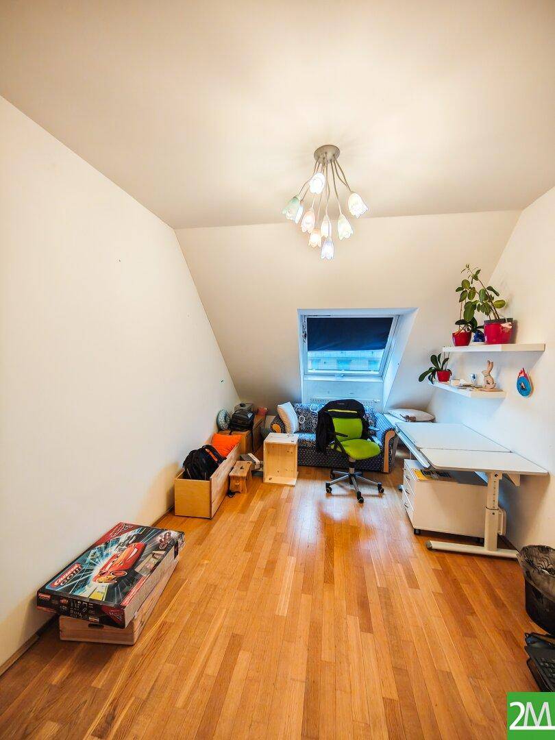 Helles Dachzimmer mit Schreibtisch, Bürostuhl und Dachfenster, ideal als Arbeits- oder Kinderzimmer.